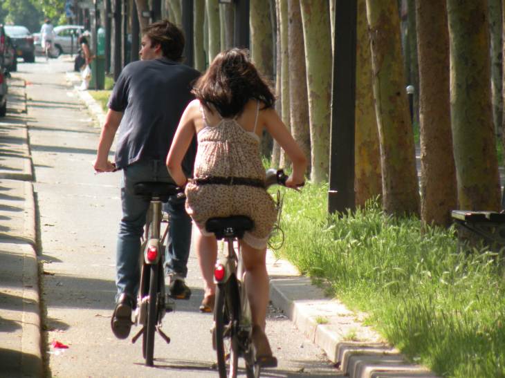  jeune femme en robe sur un vélib, roulant sur une piste cyclable